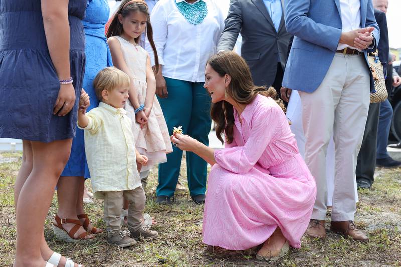 The duchess picks a flower and speaks to children on a visit to the Memorial Wall to remember victims of Hurricane Dorian in 2019 at the Memorial Garden in Abaco, Bahamas.