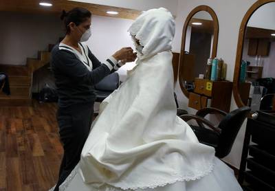 A hair dresser wearing a mask puts the finishing touches on Palestinian bride Bara'a Amarneh before she leaves the beauty salon in the Palestinian Deheisheh refugee camp near the West Bank city of Bethlehem. AFP