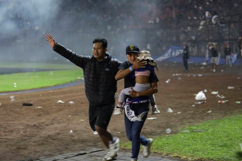 Football fans carry a girl away from a clash between fans at Kanjuruhan Stadium in Malang, East Java, Indonesia, where 174 people died in violence. EPA