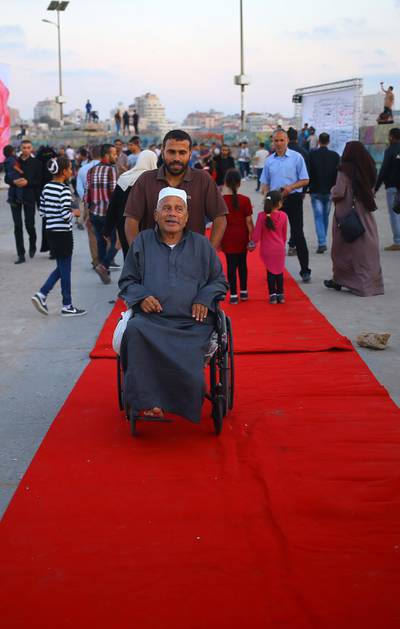 Palestinians walk on the red carpet during a film festival showcasing films focusing on human rights, in Gaza City on May 12, 2017. - The festival, which is in its third year, coincides with the Cannes Film Festival and aims to show that there is an alternative to the catwalks and glamour of its French counterpart, Saworki said. (Photo by MOHAMMED ABED / AFP)