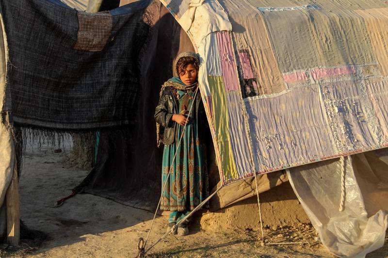 In this photograph taken on December 28, 2019, an internally displaced Afghan girl looks on as she stands outside a temporary home at a refugee camp in Khost province. (Photo by FARID ZAHIR / AFP)