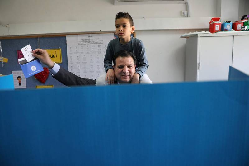 Ayman Odeh, leader of Hadash-Ta'al party, holds up his ballot paper as he stands behind a voting booth and carries his son on his shoulders as Israelis began voting in a parliamentary election, at a polling station in Haifa, Israel April 9, 2019. REUTERS/Ammar Awad