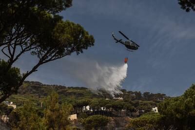 A helicopter dumps water on fires described by civil defence workers as '90% under control' following a round-the-clock battle to extinguish it before it could reach houses. All photos: Elizabeth Fitt
