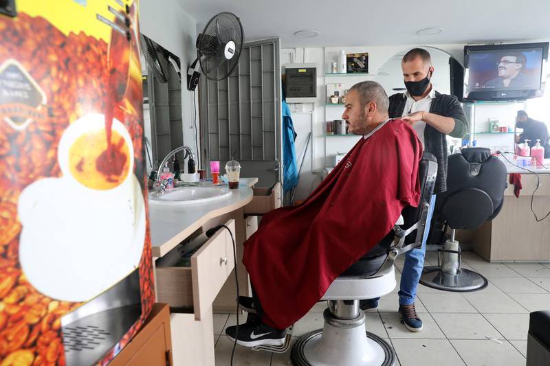 A hairdresser wearing a face mask cuts the hair of a customer in a salon in Nicosia, Cyprus. The government has removed some restrictions, with some businesses allowed to re-open while following strict rules for hygiene. EPA