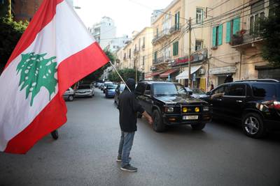 A Lebanese anti-government protester waves his national flag as he stands in the middle of a road in Beirut on November 5, 2019.  Demonstrators in Lebanon blocked key roads and prevented some public institutions from opening after mass rallies showed political promises had failed to extinguish the unprecedented protest movement. / AFP / Patrick BAZ
