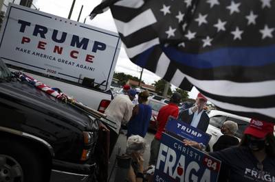 Supporters of U.S. President Donald Trump hold signs during a rally outside an early voting polling location for the 2020 Presidential election in Miami, Florida, U.S., on Monday, Oct. 19, 2020. The Biden campaign and its supporters have booked $15.4 million worth of media advertising on Oct. 19, compared with $6 million booked by the Trump campaign and its backers, according to data by ad-tracking firm Advertising Analytics. Photographer: Marco Bello/Bloomberg