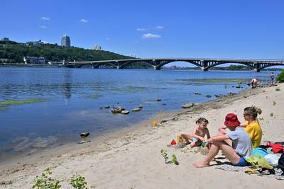 A family on the shores of the Dnipro river that runs through the Ukrainian capital of Kyiv on July 2, 2022. AFP
