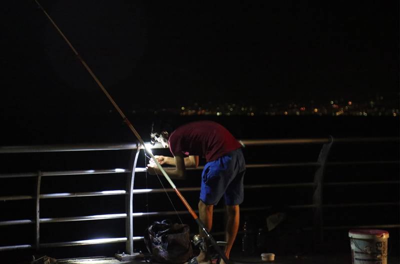 A fisherman uses a headlamp at the seaside corniche in Beirut, Lebanon. EPA