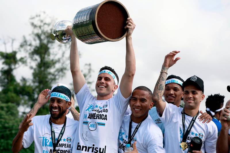 TOPSHOT - Brazil’s Gremio goalkeeper Marcelo Grohe (2-L) raises the Copa Libertadores 2017 trophy next to his teammates, as he celebrates their victory in Porto Alegre, Brazil on November 30, 2017. 
Brazilian side Gremio won their third Copa Libertadores crown on Wednesday with a 2-1 triumph over Argentina's Lanus in La Fortaleza stadium. With the victory, Gremio qualified directly into the semi-finals of the Club World Cup in December, where they'll face either Africa's Wydad Casablanca or CONCACAF representative Pachuca of Mexico. / AFP PHOTO / ITAMAR AGUIAR