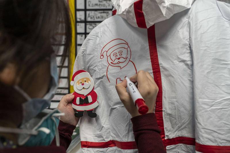 Medical staff member Anne Aguilar draws a Santa Claus figure on a coverall suit in the nursing station of the Covid-19 intensive care unit on Christmas Eve at the United Memorial Medical Centre in Houston, Texas. AFP
