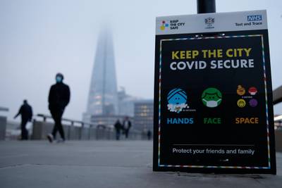 Commuters pass a Covid-19 advice board on London Bridge at sunrise. Getty Images