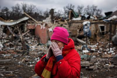 Irina Moprezova, 54, stands in front of a house that was damaged by an air strike in Irpin. AFP