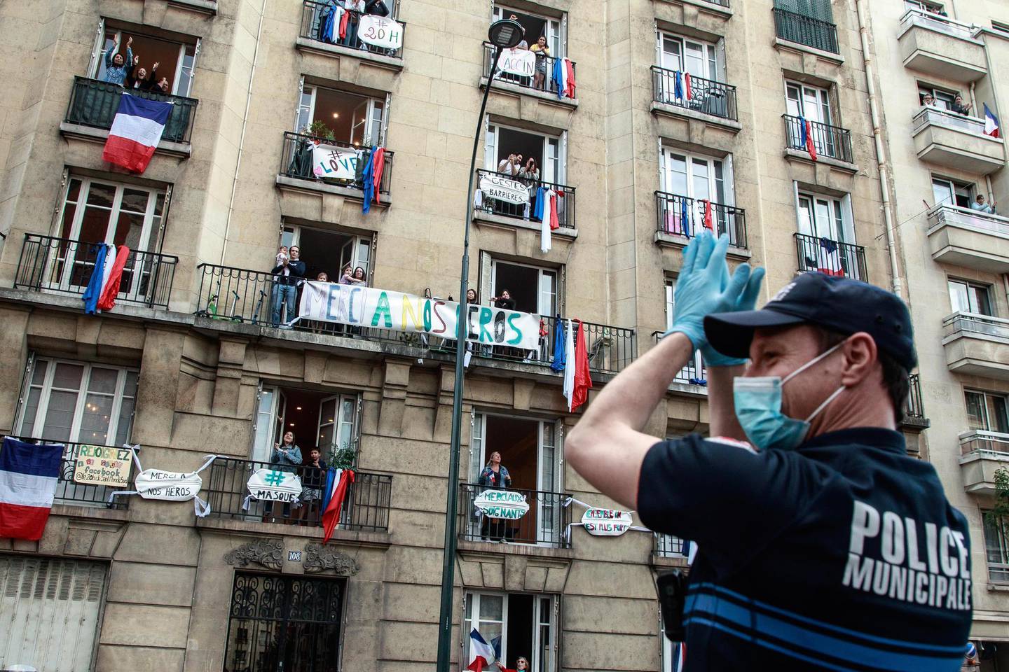 epa08398072 A police officer applauds in front of a building decorated with French flags and support messages for health employees as the neighbors applaud from their windows to support French medical staff amid the ongoing coronavirus COVID-19 pandemic in Saint Mande, near Paris, France, 02 May 2020. During the lockdown, people in many European cities are taking at least a minute each night to applaud in gratitude for health workers and police.  EPA/CHRISTOPHE PETIT TESSON