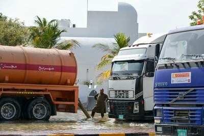 Workers pump floodwaters from the roads into tankers in Fujairah city. Khushnum Bhandari / The National
