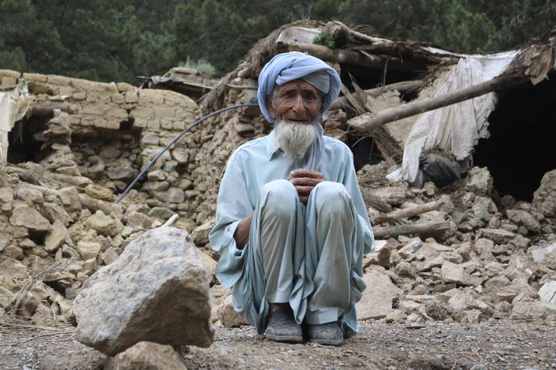An Afghan man sits near what's left of his house. AP