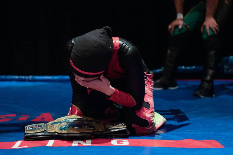 Hijab-wearing Malaysian wrestler Nor "Phoenix" Diana wipes away tears after winning the Wrestlecon championship belt
