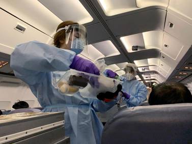 Flight attendants wearing protective clothing on a chartered plane bringing Canadians home from areas affected by the virus. Reuters