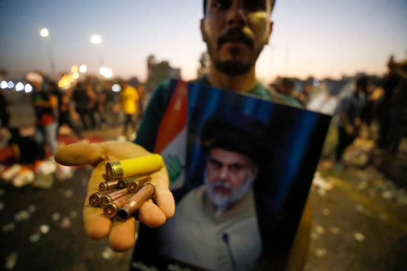A supporter of Mr Al Sadr carries bullet casings and a spent shotgun shell in the Green Zone. AFP