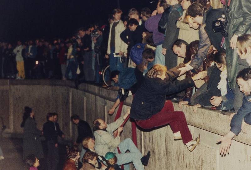 East Berliners get helping hands from West Berliners as they climb the Berlin Wall. AP Photo