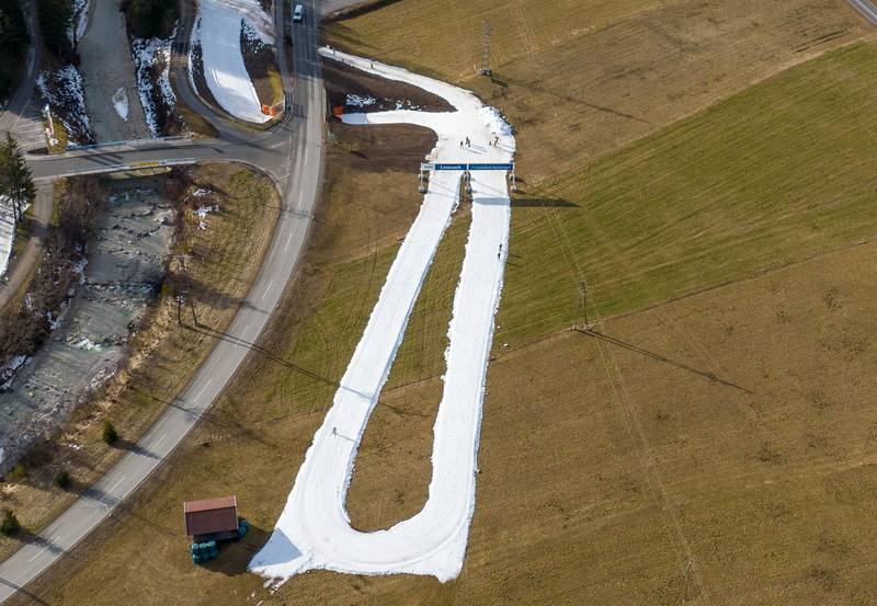 This aerial view taken on January 2, 2023 shows ski tourists on ski slopes amidst snow-free meadows in Leutasch, Austria.  - Due to the warm temperatures of the last few days, there is a lack of snow in the ski areas.  (Photo by Daniel LIEBL  /  various sources  /  AFP)  /  Austria OUT