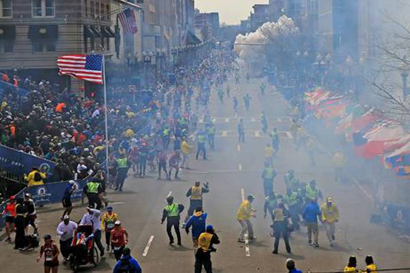 People react as an explosion goes off near the finish line of the 2013 Boston Marathon in Boston. AP Photo/The Boston Globe, David L Ryan
