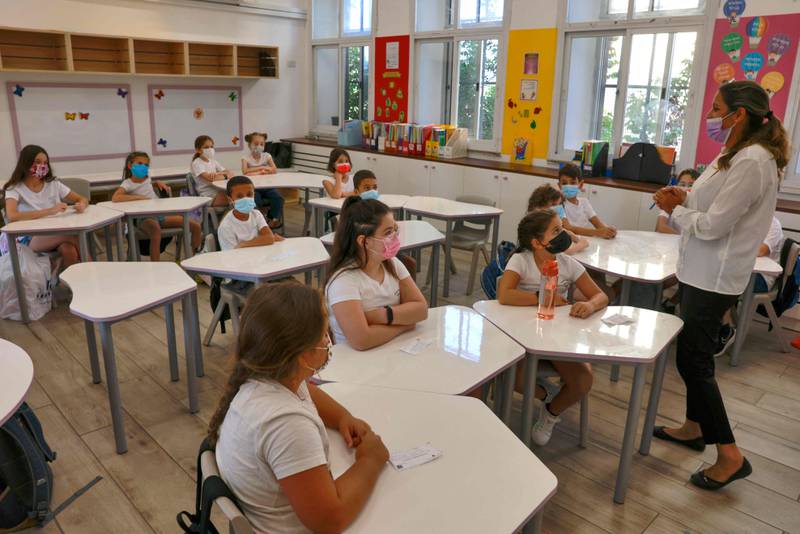 Pupils listen to a teacher on their first day back at school. AFP