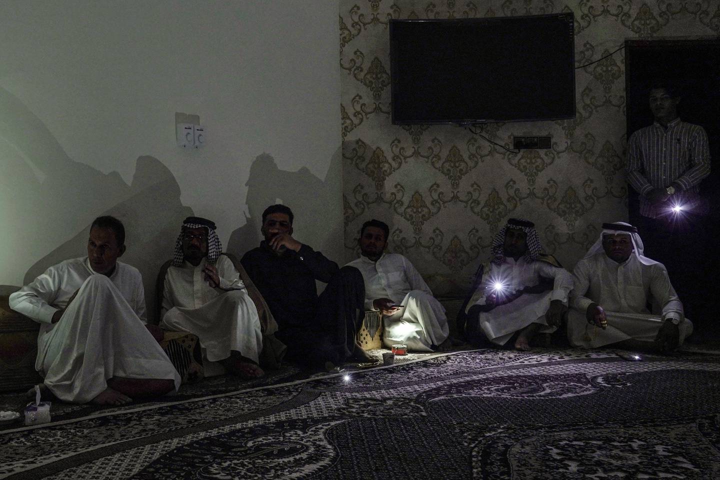 Residents of Nasiriyah attend a meeting with election candidate Alaa Al Rikabi during one of the frequent power cuts in the southern Iraqi city. Haider Husseini / The National                                                                       