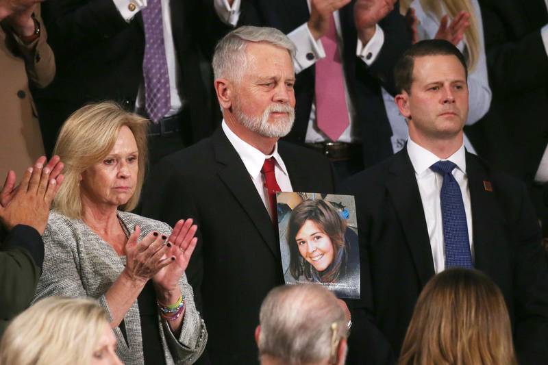 Carl Mueller (C) holds a photo of his daughter, Kayla, as his wife Marsha (L) looks on during the State of the Union address in the chamber of the US House of Representatives in Washington, DC.  Getty Images