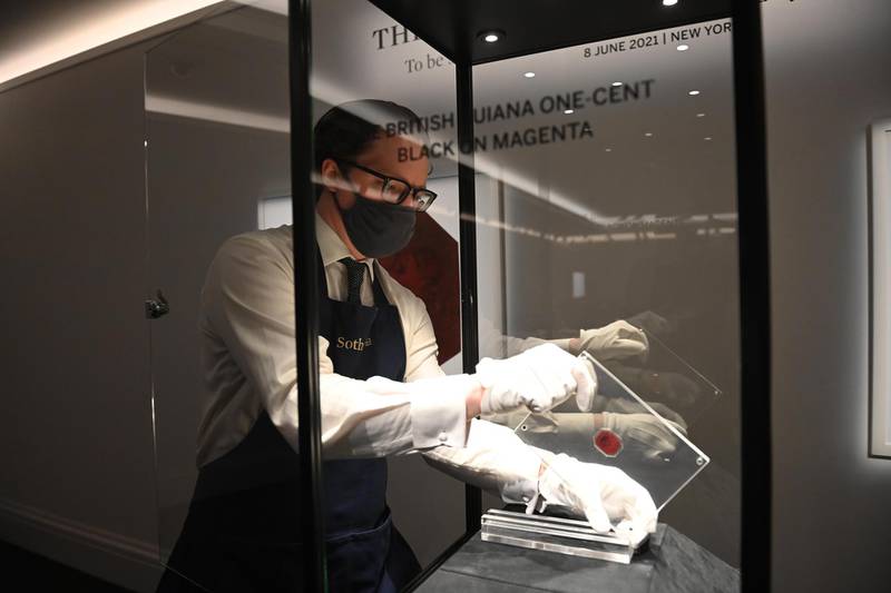 An auction worker places the British Guiana One-Cent Magenta stamp in a display case. EPA