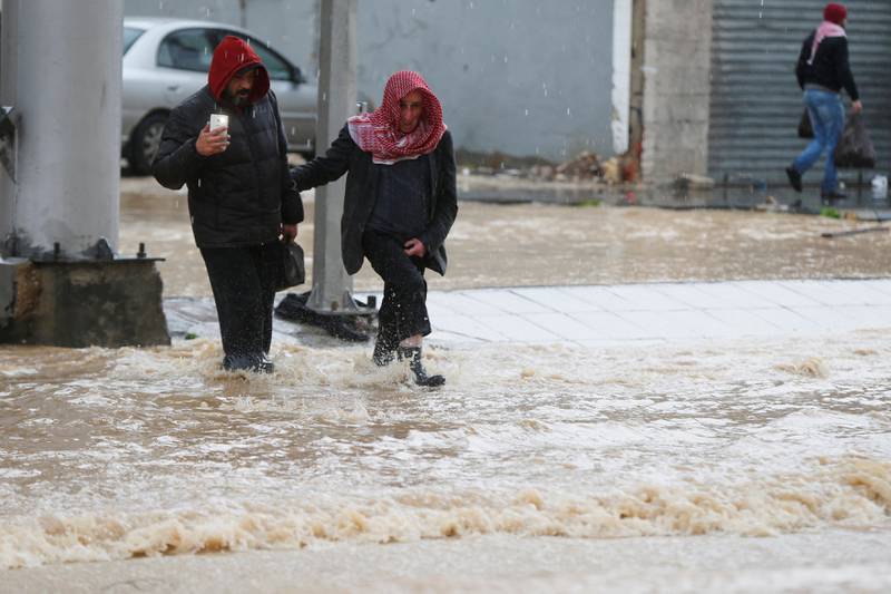 People cross a flooded street during heavy rains in Amman, Jordan, February 28, 2019. REUTERS/Muhammad Hamed