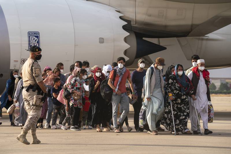 Afghan people pass a Spanish soldier after arriving on a plane at the Torrejon military base as part of the evacuation process in Madrid. AP Photo