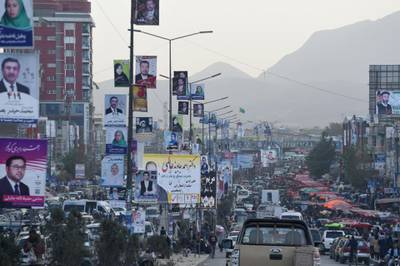 Commuters drive along a road with posters of candidates hanging from posts in Kabul. AFP