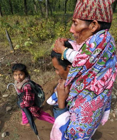 In a picture taken on February 8, 2012, Chandra Bahadur Dangi (R), a 72-year-old Nepali who claims to be the world's shortest man at 56 centimetres (22 inches) in height, is carried by his nephew Dolak Dangi on the way to his home village in Dang district, some 540 kilometres southwest of Kathmandu. Pilloried by neighbours, laughed at in freakshows and spurned by the women he admired from afar, Chandra Bahadur Dangi has always seen his tiny stature as a curse. But the 72-year-old Nepali, who claims to stand at just 56 centimetres (22 inches), is on the brink of life change as significant as a lottery win as experts prepare to test his claim to be the shortest man in history. AFP PHOTO/Prakash MATHEMA
 *** Local Caption ***  864257-01-08.jpg