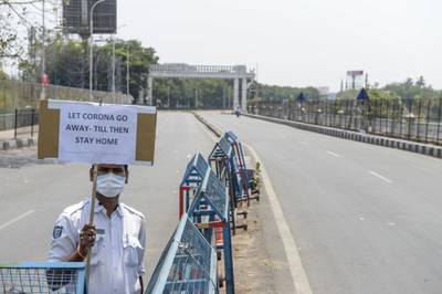A traffic policeman hold a placard advising commuters to stay home on a deserted road during the first day of a 21-day government-imposed nationwide lockdown as a preventive measure against the COVID-19 coronavirus, in Hyderabad on March 25, 2020. / AFP / NOAH SEELAM
