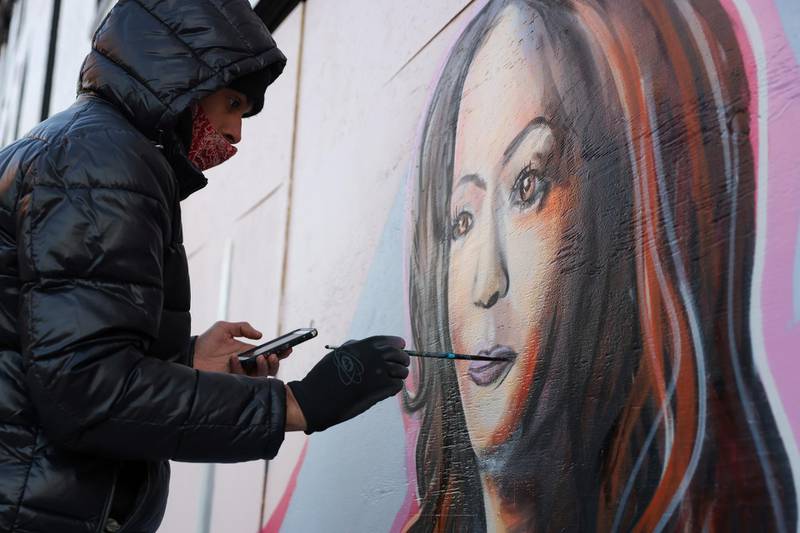 An artist works on a mural of US Vice President-elect Kamala Harris on Martin Luther King Day in Washington. Reuters