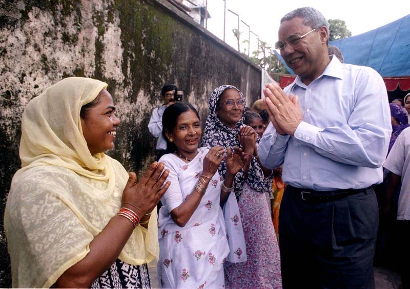 Powell clasps his hands in traditional Indian greeting as he meets women in Bombay in September  1997. Reuters