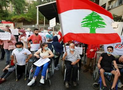A man in a wheelchair flies a Lebanese flag during a protest demanding justice for the victims of last year's Beirut port blast.