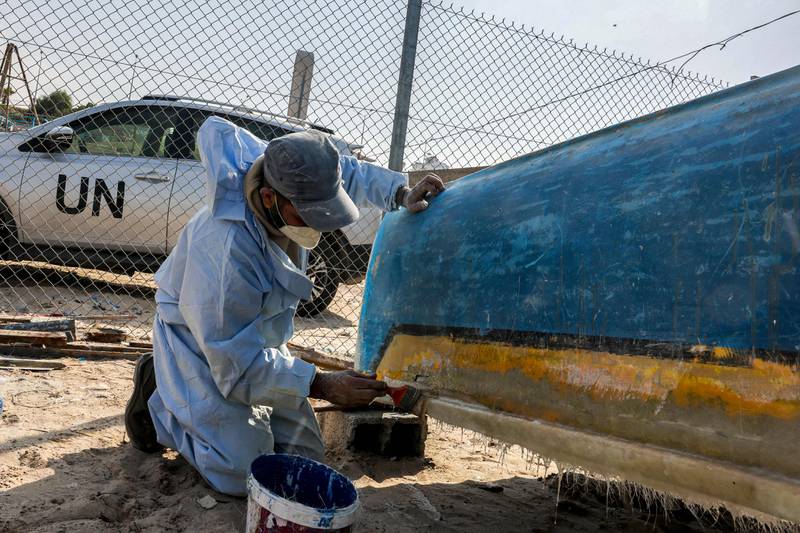 A craftsman uses fibreglass to repair a fishing boat at a workshop supervised by the United Nations at the Gaza seaport on November 29, 2022, after Israel allowed the material to the Palestinian enclave for the first time since 2007 under international supervision.  (Photo by Mohammed ABED  /  AFP)