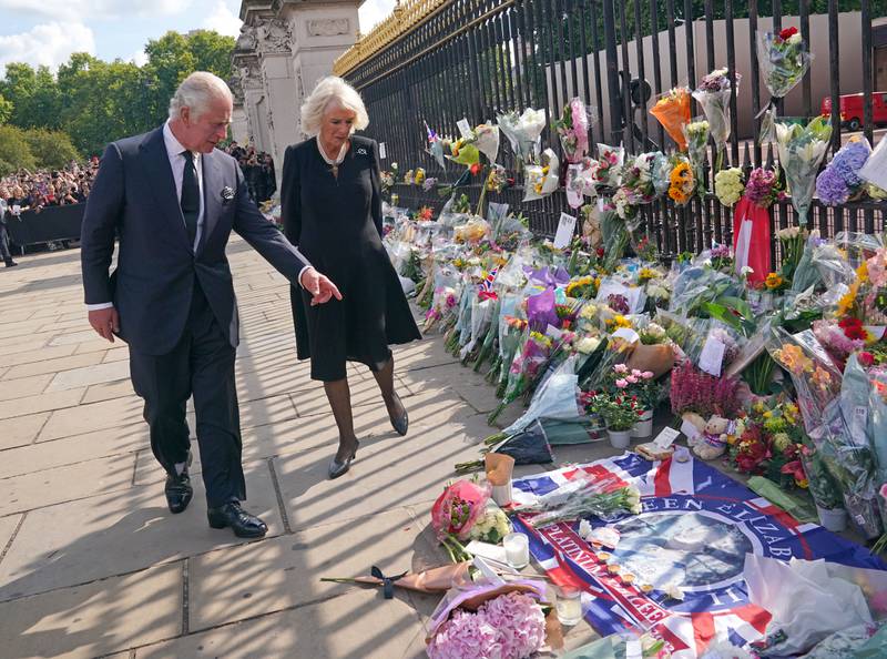 King Charles and the queen consort view tributes left outside Buckingham Palace, London, after the death of Queen Elizabeth on Thursday. PA