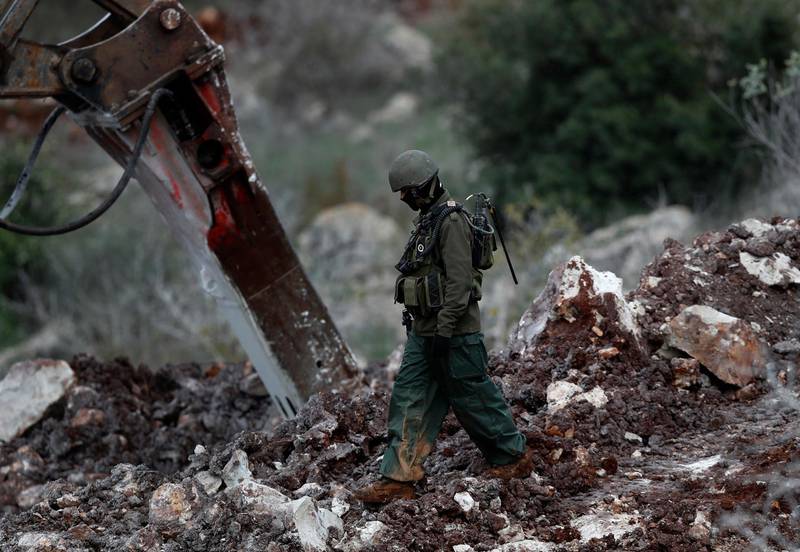 An Israeli soldier walks next to a digger. AP Photo