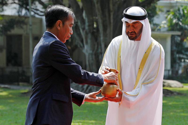 Mr Widodo and Sheikh Mohamed hold a pitcher as they plant a tree during a welcoming ceremony at the presidential palace. Willy Kurniawan / Reuters
