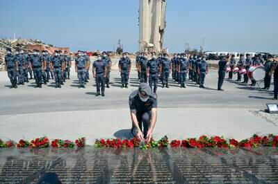 Members of the Lebanese Internal Security Forces lay flowers in front of a memorial to the victims of the explosion in Beirut's port last year.