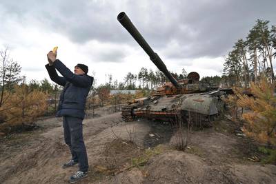 A man takes a selfie in front of a destroyed Russian tank in the village of Andriivka. AFP