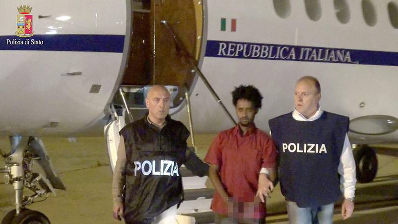 Medhanie Yehdego Mered, centre, is pictured with Italian policemen as they land at Palermo airport, Italy, following his arrest in Khartoum, Sudan, on May 24. Italian police department/Handout via Reuters