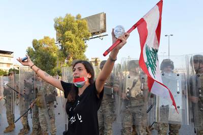 epa08665134 An anti-government protester carries a national flag as she shouts slogans in front of the Lebanese army soldiers during a protest on the road leading to the Presidential palace in Baabda, east Beirut, Lebanon, 12 September 2020. Hundreds of anti-government protesters gather outside the Presidential palace to protest against politicians, security and judicial officials, many of whom knew about the storage of the chemicals that exploded in Beirut's port on 04 August, and did nothing.  EPA/WAEL HAMZEH