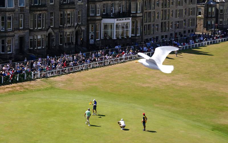 A seagull flies past as USA's Tony Finau and Spain's Adri Arnaus tee off the 18th during day three of The Open at the Old Course, St Andrews. 