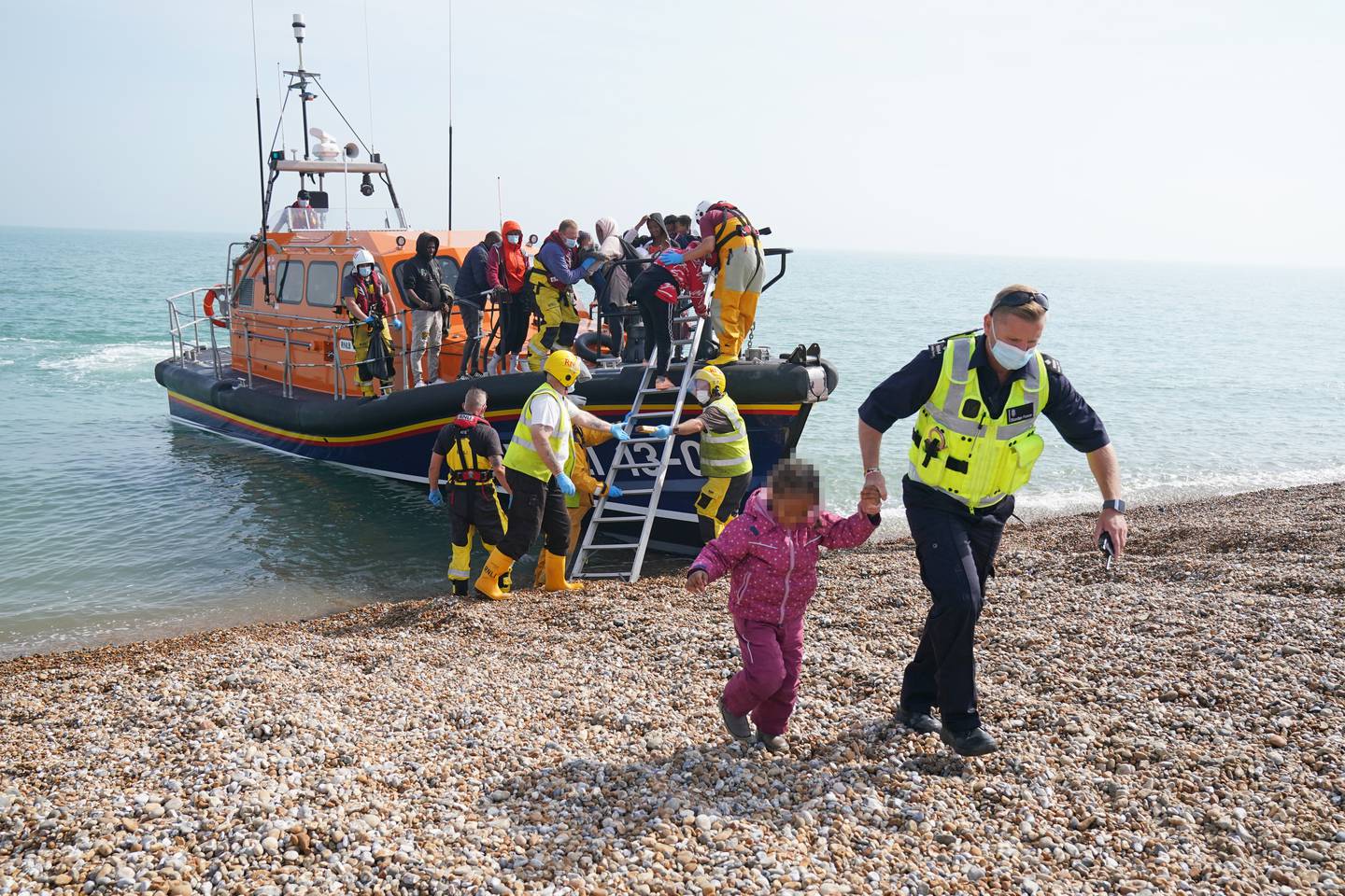 A little girl is helped ashore by a Border Force agent in Kent after arriving on a small boat from France. Getty 