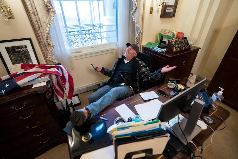 A supporter of US President Donald J. Trump sits on the desk of US House Speaker Nancy Pelosi, after supporters of US President Donald J. Trump breached the US Capitol security in Washington, DC. EPA