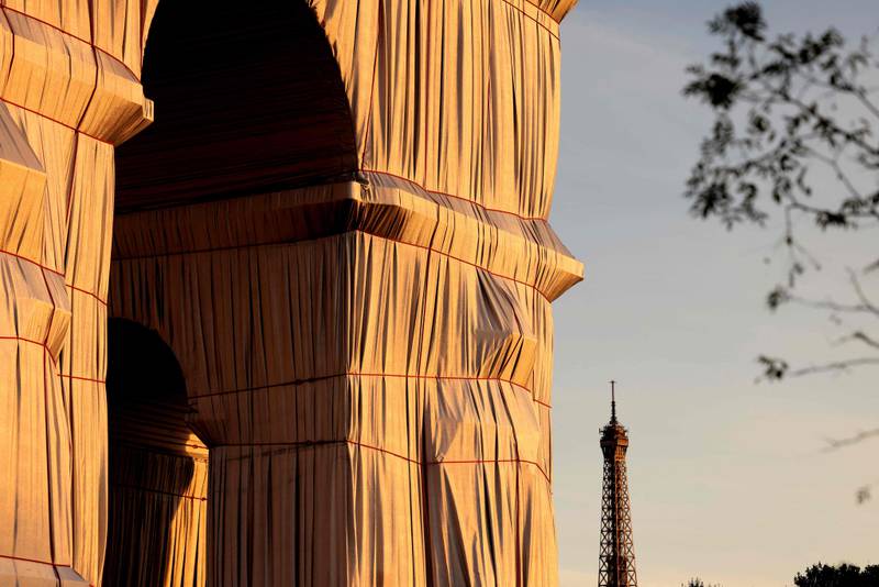 Arc de Triomphe is shown wrapped in fabric, against the Eiffel Tower in the background. The building remained covered for 16 days. AFP