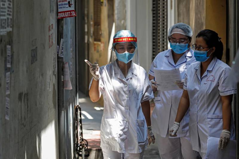 Healthcare workers are seen at a lane near the house of a Covid-19 patient as they investigate infection links in Hanoi, Vietnam. Reuters
